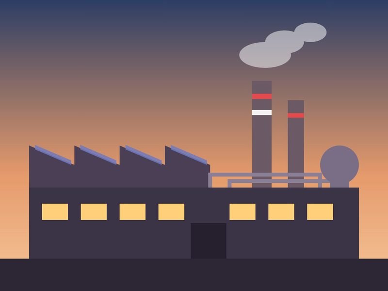 Manufacturing plant with a sawtooth roof and two chimneys at sunset